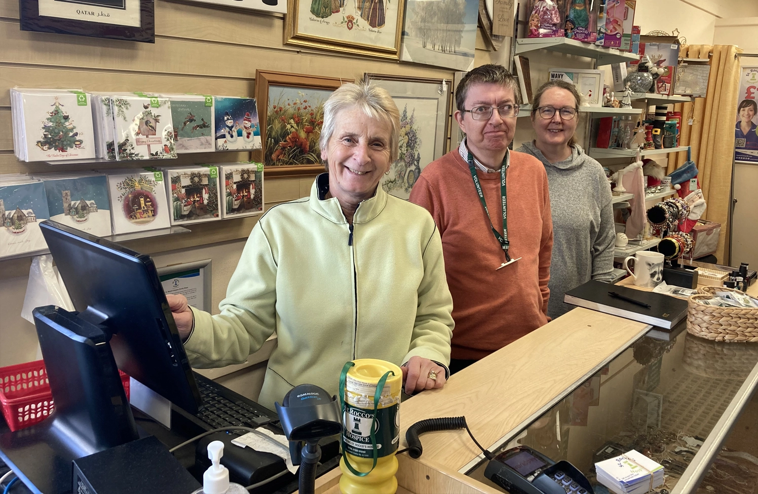.A photo of shop volunteers together smiling at a customer service area